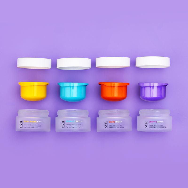 Four SVR Biotic skincare jars with colorful inner lids and white caps arranged on a purple background.