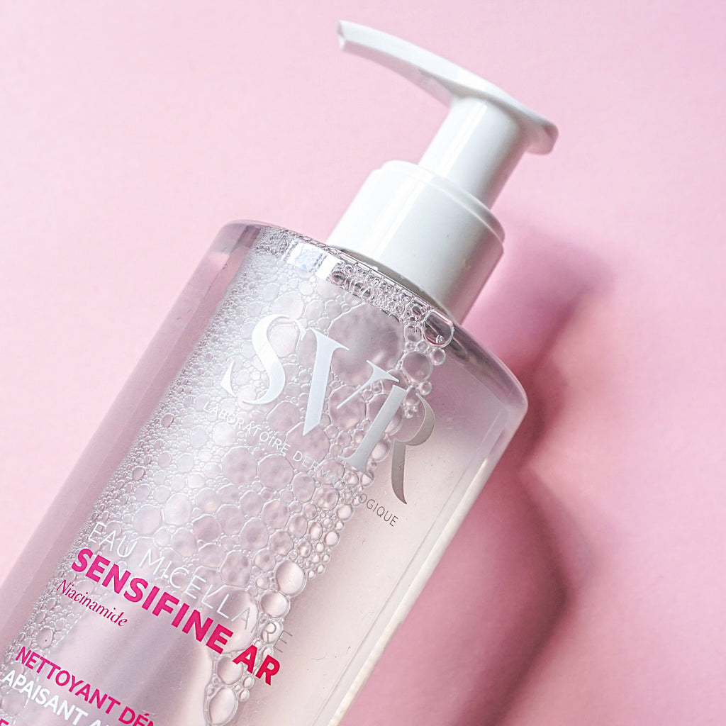 Clear plastic bottle of SVR Sensifine AR Micellar Water with white pump dispenser on pink background.