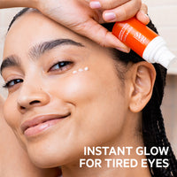 Woman applying SVR [C] Eye Biotic cream from an orange pump bottle onto her under-eye area for a radiant, hydrated look.