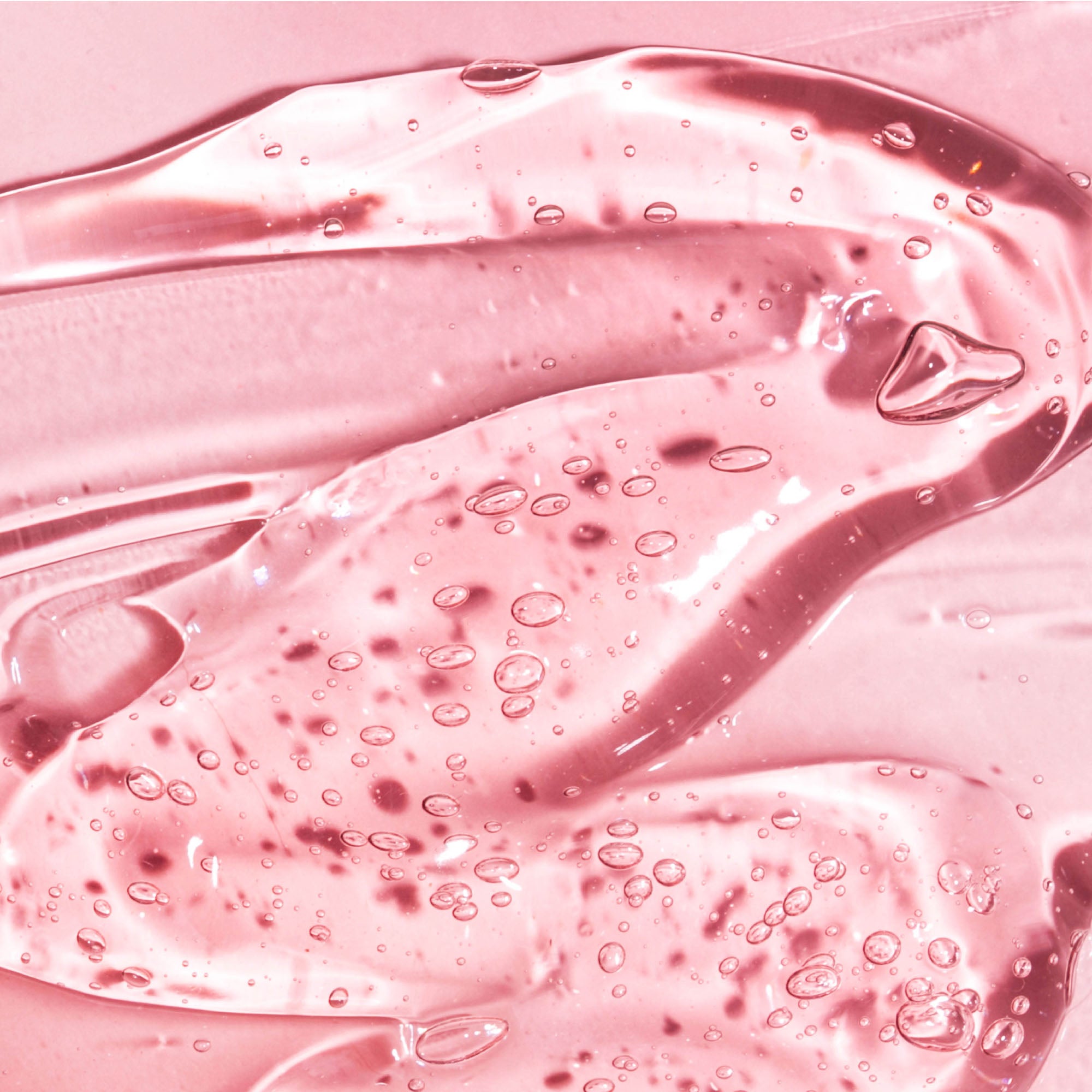 Clear pink gel texture with small air bubbles, smooth and glossy surface.