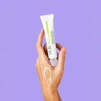 Hand holding a white SVR Sebiaclear Active Gel tube against a purple background with a gel swatch on the skin.