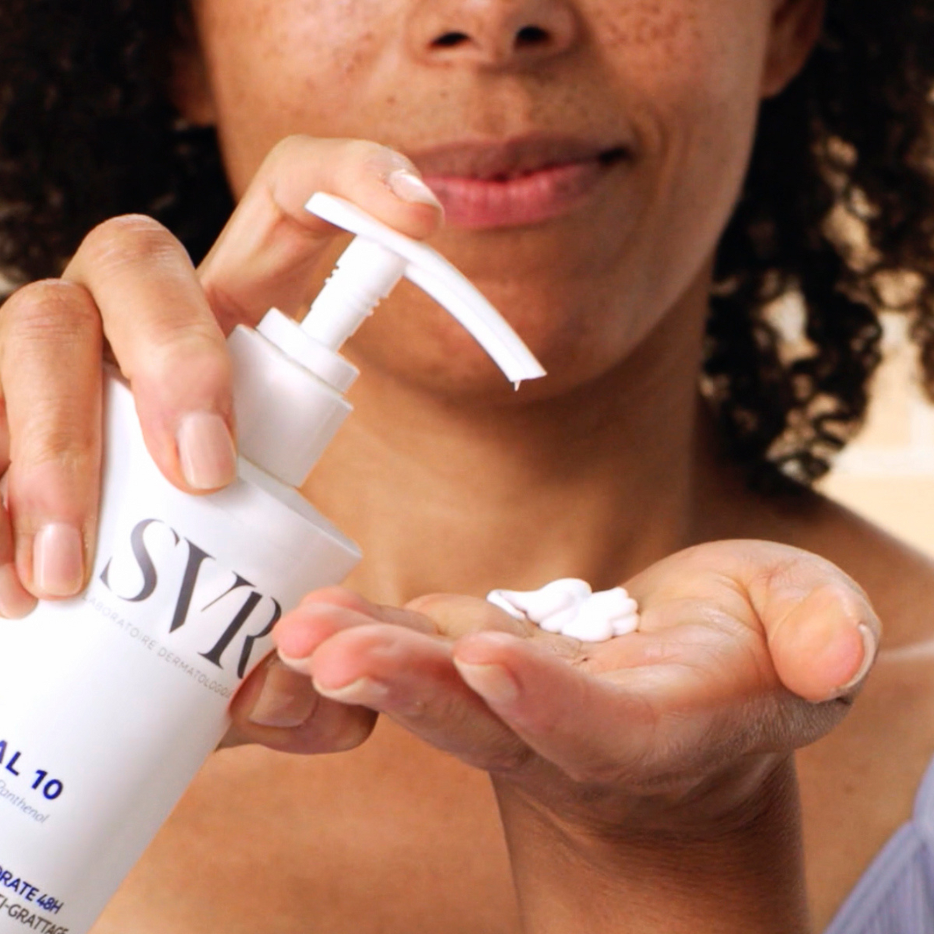 White bottle of SVR XERIAL 10 body lotion with pump dispensing cream onto hand.